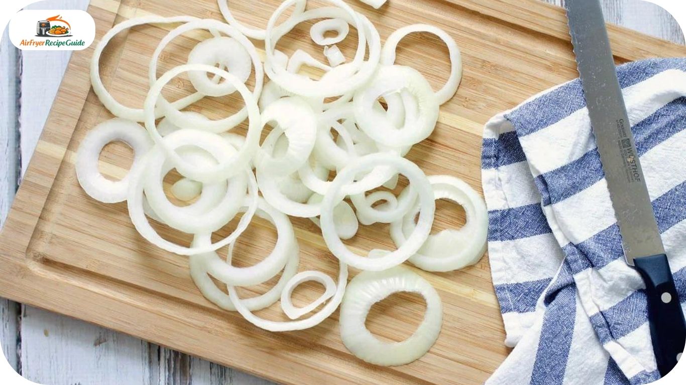 Fresh yellow onion sliced into thick rings on cutting board